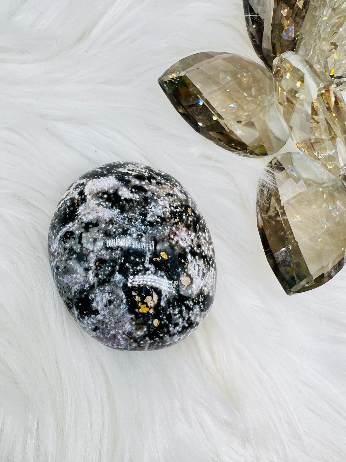 An Ocean Jasper Palmstone with sparkly with black, grey, white and brown colours.