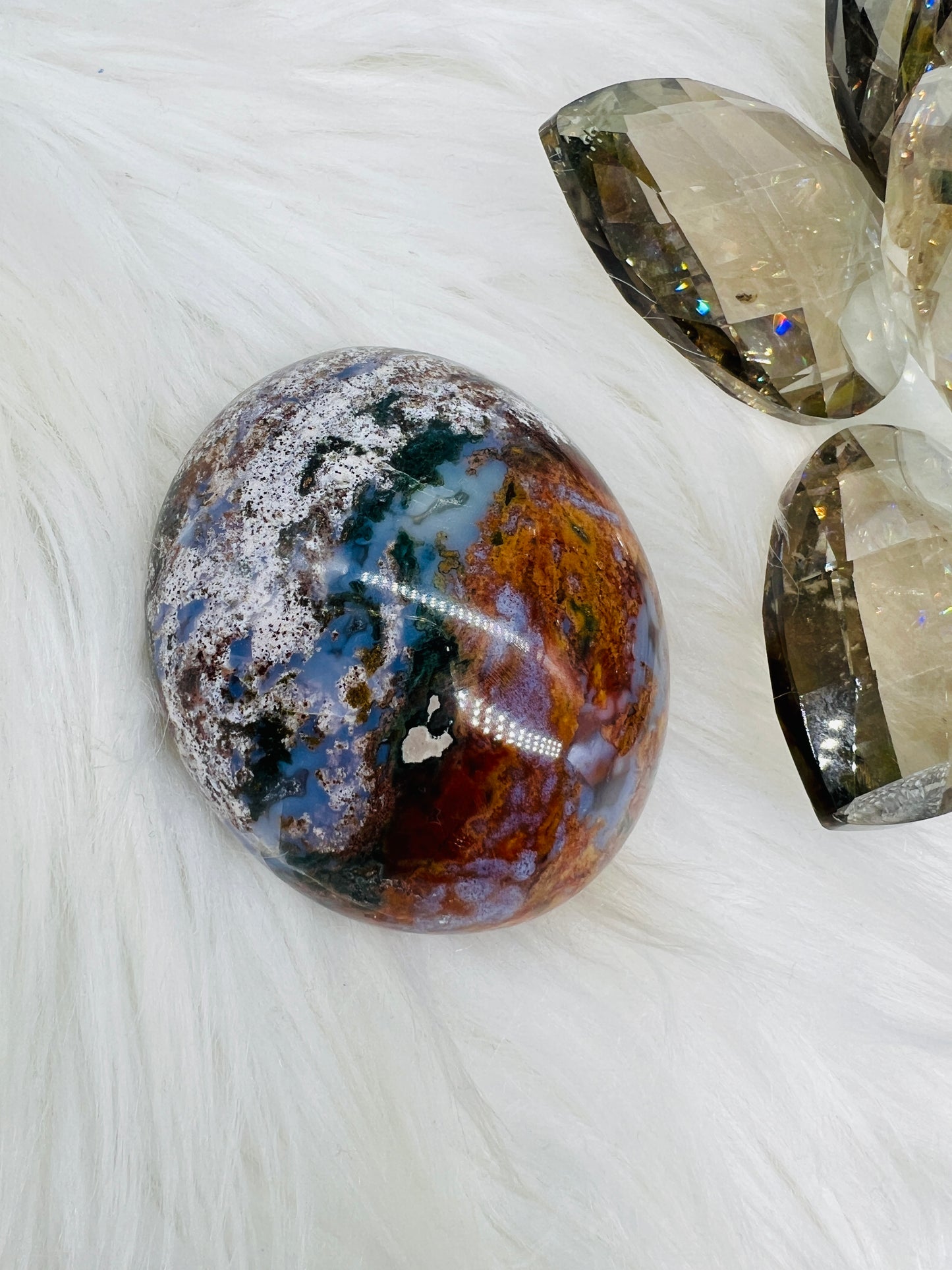 An Ocean Jasper Palmstone with red white, yellow, lilac patterns resembling ocean waves.