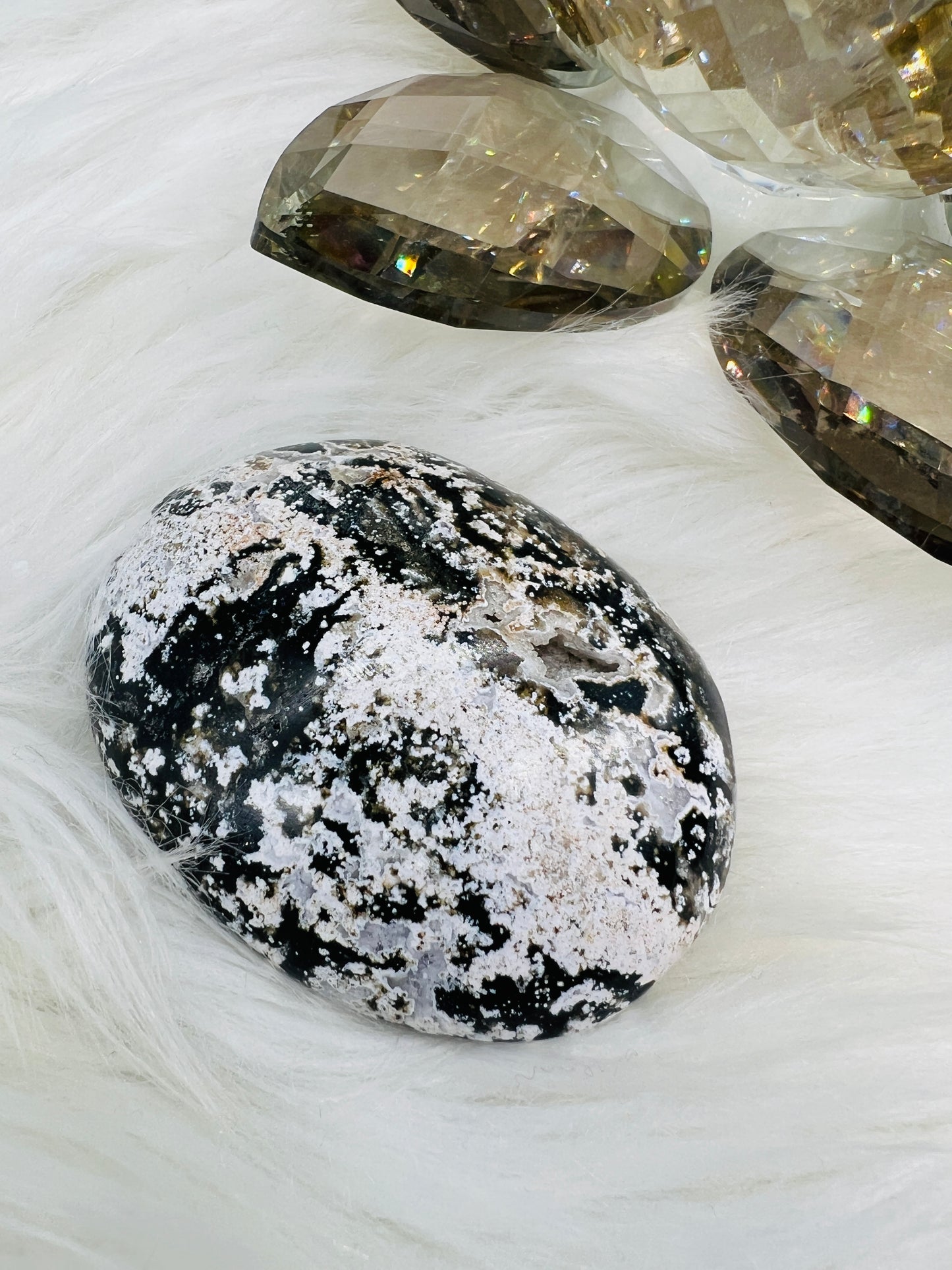 An Ocean Jasper palmstone with druzy pockets and black and white patterns resembling ocean waves.