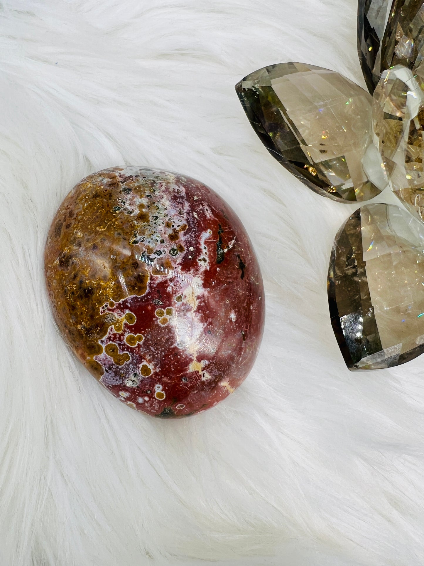 An Ocean Jasper Palmstone with red white and yellow patterns resembling ocean waves.