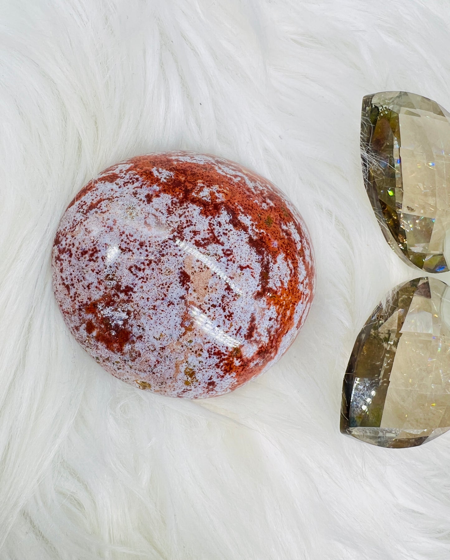 An Ocean Jasper Palmstone with red and white/lilac patterns resembling ocean waves.