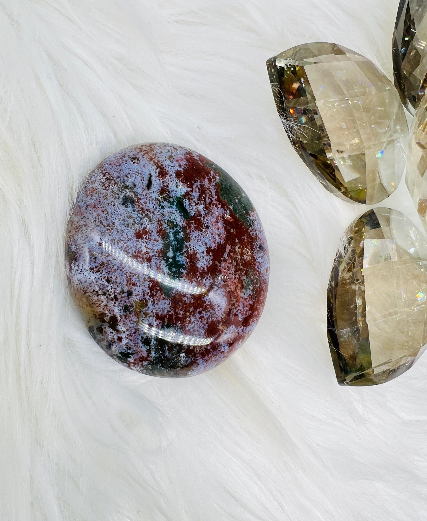 An Ocean Jasper Palmstone with red, green, white/lilac patterns resembling ocean waves.