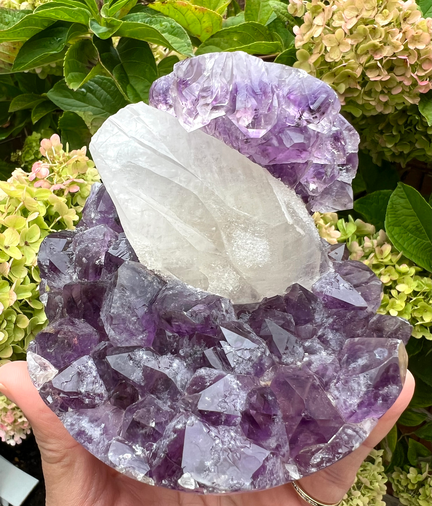 A natural amethyst geode sphere with a large sparkly coated calcite in the centre, from Brazil.