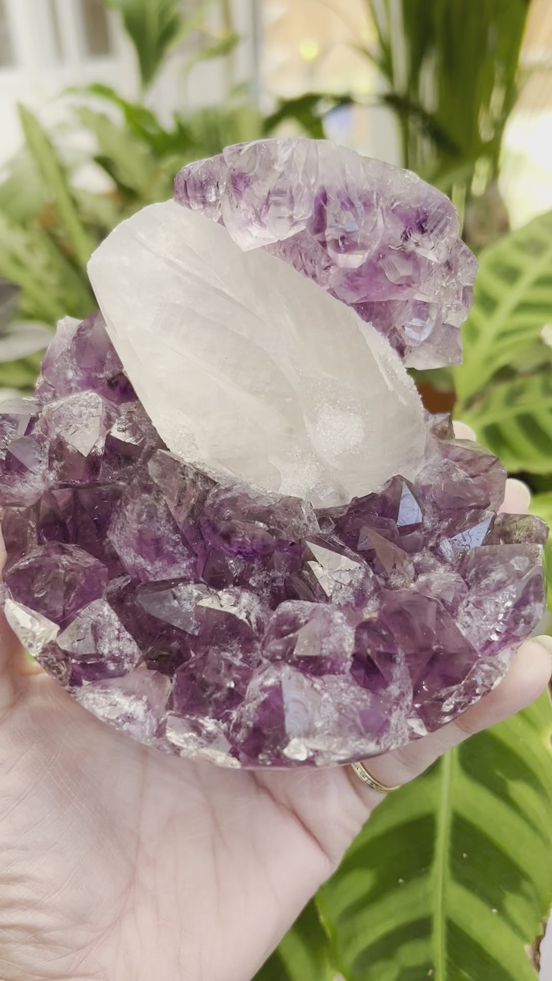 A video of a natural amethyst geode sphere with a large sparkly coated calcite in the centre, from Brazil.